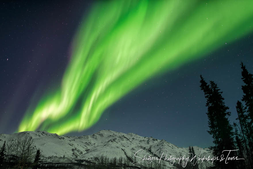 Aurora Borealis gleams over mountain peaks