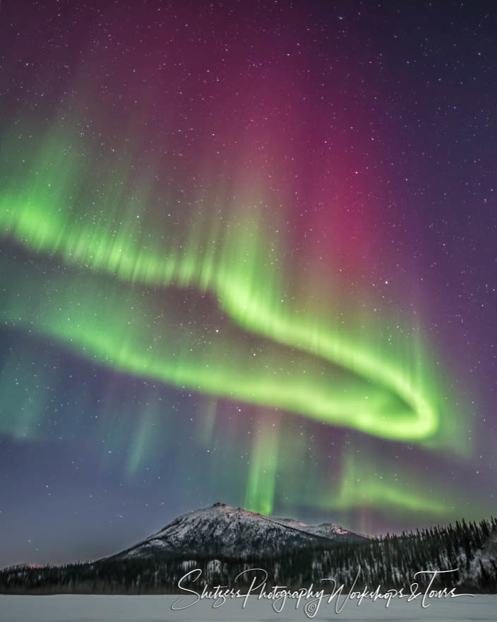 Circular shaped Northern Light forms over mountain peak