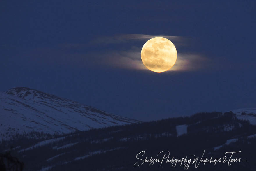 Full moon shines brightly over snowy mountain peaks