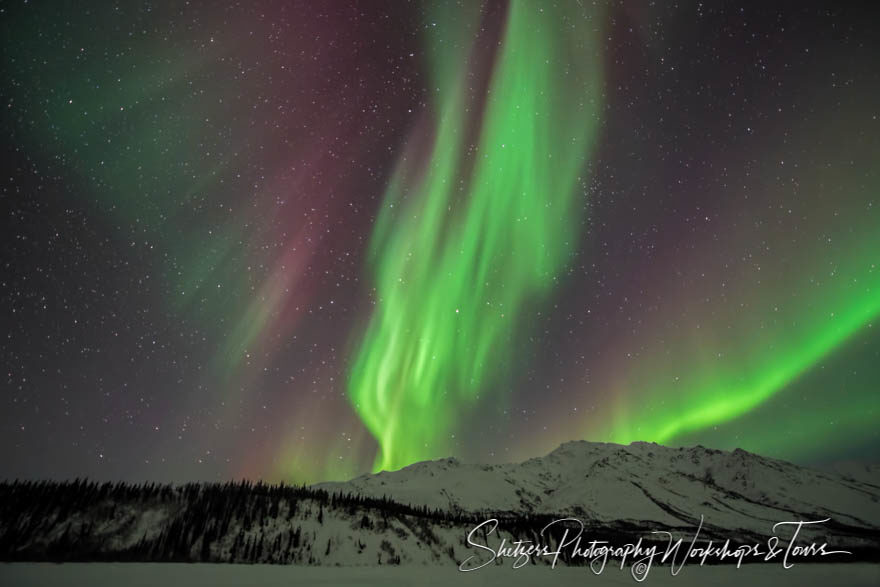 Northern lights dance on mountain tops