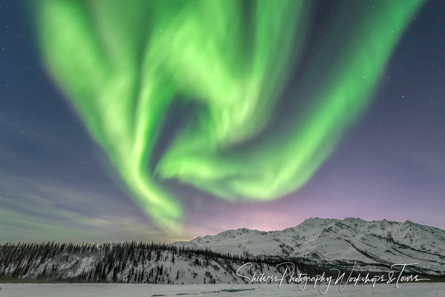 Northern lights pattern forms over mountain peaks