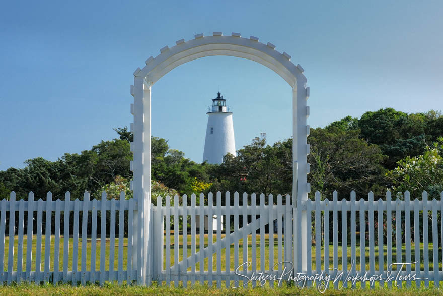 Ocracoke Lighthouse framed inside white picket fence gate