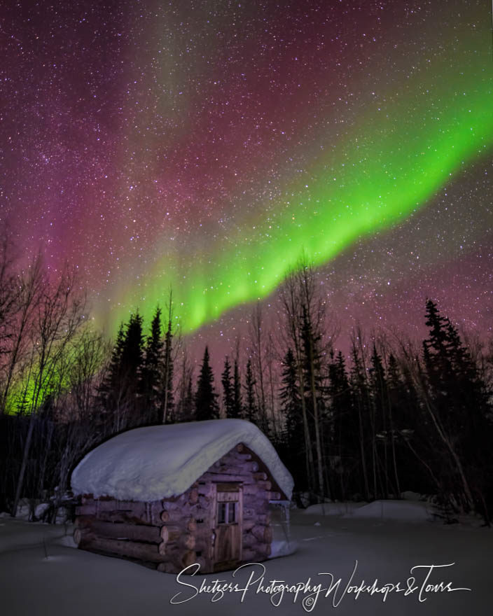 Snowy cabin illuminated by Northern Lights